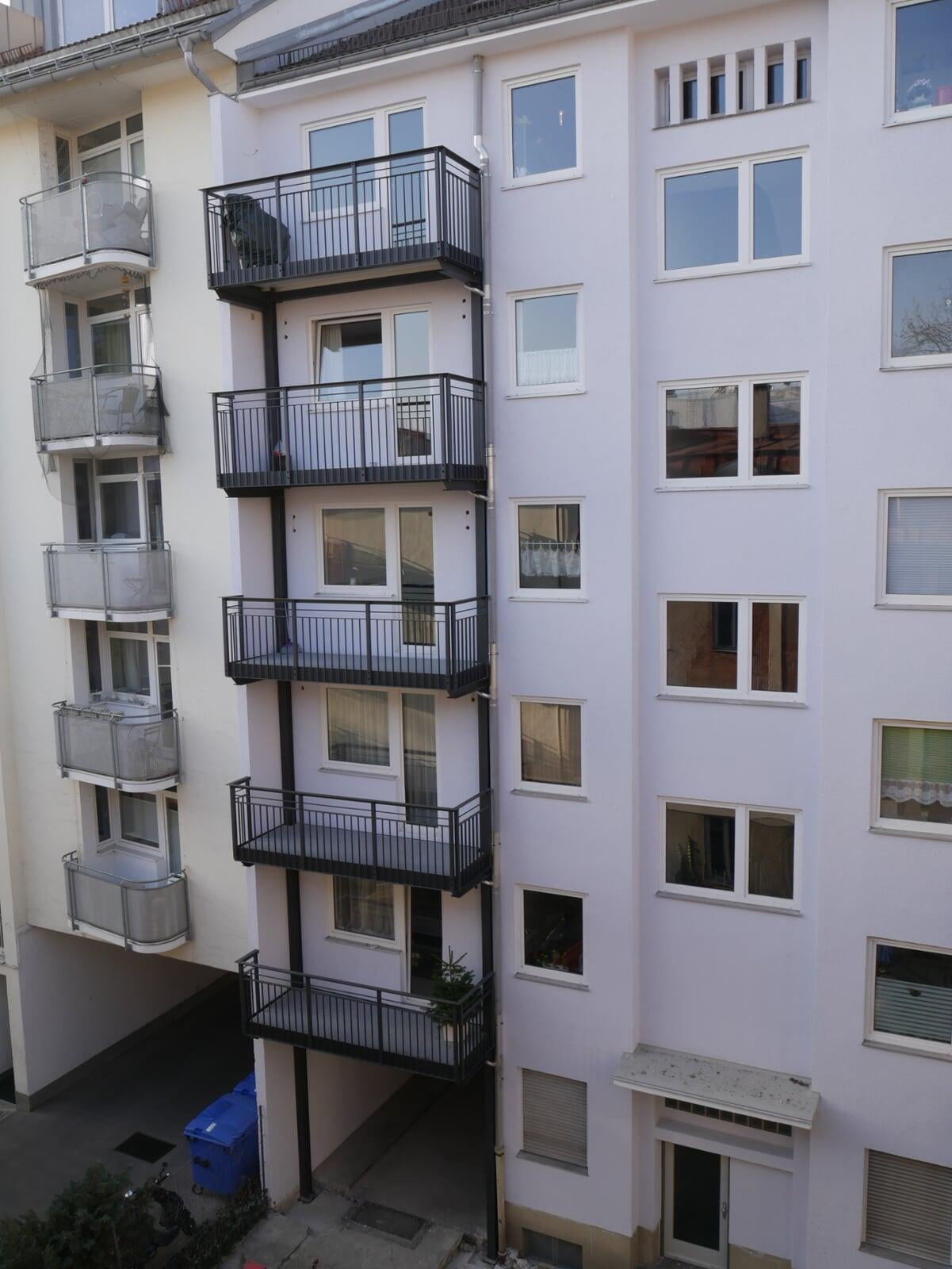 Das Foto zeigt einen Balkonturm mit mehreren übereinander angeordneten - "gestapelten" Balkonen. Besonderheit hier ist die statische Tragkonstuktion der "Hängebalkone" über zwei, senkrecht an der Außenwand verlaufenden Stahlpfeilern, sogenannten Lisenen.